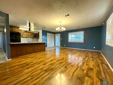 Kitchen featuring open floor plan, light countertops, a chandelier, dark wood-type flooring, and black refrigerator