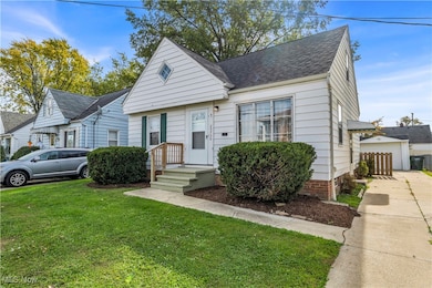 View of front of property with a front yard, roof with shingles, and a garage