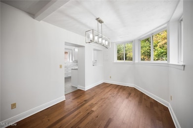 Unfurnished dining area with dark hardwood flooring and a chandelier