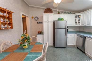 Kitchen with ornamental molding, white cabinets, lofted ceiling, and appliances with stainless steel finishes