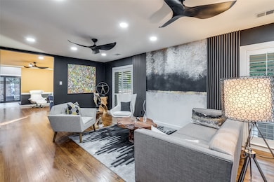 Refined formal living room blending effortlessly into the dining area, enhanced by custom wood accents, wood flooring, dual ceiling fans, and elevated décor.