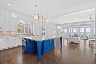 Kitchen with blue cabinetry, white cabinetry, backsplash, decorative light fixtures, and light stone countertops