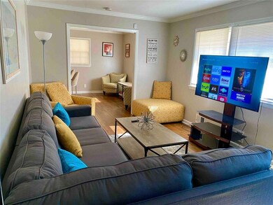 Living room with wood finished floors, plenty of natural light, and crown molding