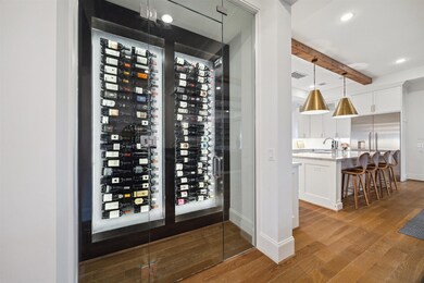 The glass-enclosed wine cellar is a stunning focal point, designed to hold 84 bottles, and is conveniently located across from the wet bar, which seamlessly overlooks the kitchen, breakfast area, and living room, creating the ultimate space for effortless entertaining.