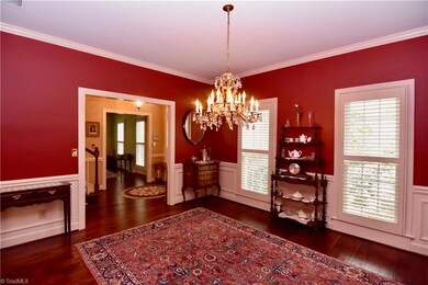 Formal dining room with hardwood floors, plantation shutters, wainscott panels.