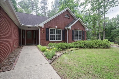 View of exterior entry with brick siding, a yard, 