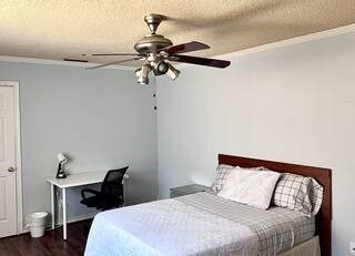 Bedroom with ornamental molding, dark wood-style flooring, a textured ceiling, and a ceiling fan