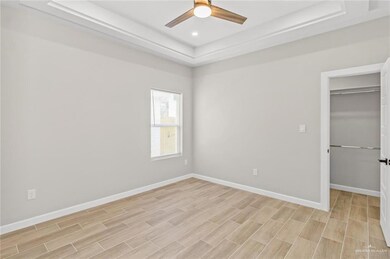 Unfurnished bedroom featuring a tray ceiling, baseboards, light wood-type flooring, and recessed lighting