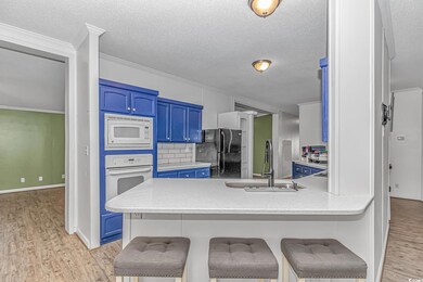 Kitchen with blue cabinets, white appliances, a sink, light wood-style flooring, and ornamental molding