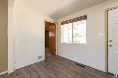 Spare room featuring dark wood-type flooring and baseboards