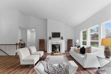 Living area with wood finished floors, high vaulted ceiling, and a premium fireplace