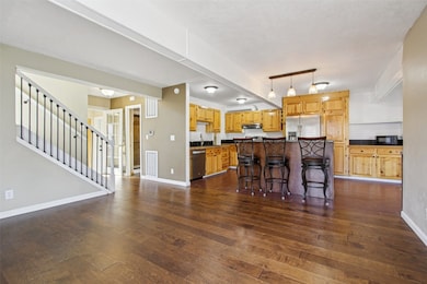 Kitchen featuring a breakfast bar, dark wood-style flooring, a kitchen island, appliances with stainless steel finishes, and hanging light fixtures