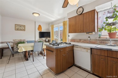 Kitchen with ceiling fan, dishwasher, stainless steel gas stovetop, light tile flooring, and sink