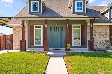 Entrance to property with a lawn, a porch, a shingled roof, and brick siding