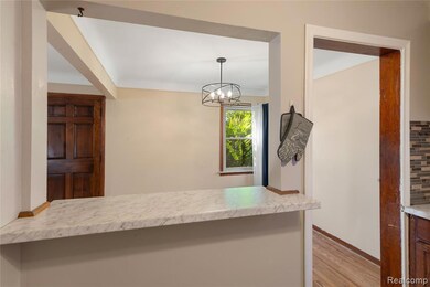 Kitchen featuring decorative light fixtures, light wood-style flooring, a chandelier, and decorative backsplash