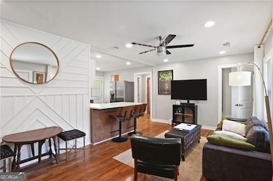 Living area with dark wood-style floors, ceiling fan, baseboards, and recessed lighting