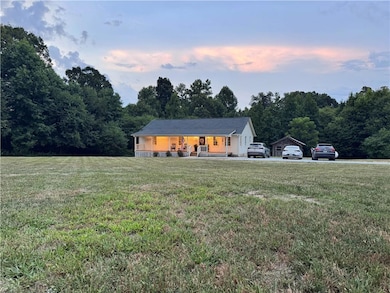 View of front of home featuring covered porch, a front lawn, and a forest view