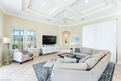 Living room featuring coffered ceiling, light tile patterned floors, ceiling fan, ornamental molding, and beamed ceiling