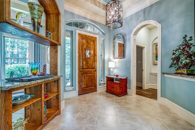 Foyer with tile floors, 8 inch baseboards, custom art niche, coffered ceiling and cased arched entries.