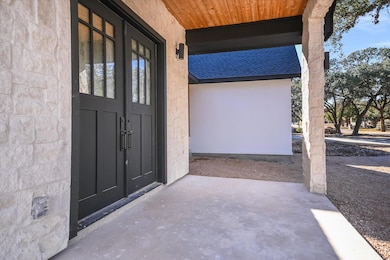 View of exterior entry featuring a shingled roof, covered porch, and stucco siding
