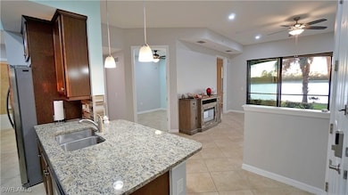 Kitchen featuring ceiling fan, sink, light stone c