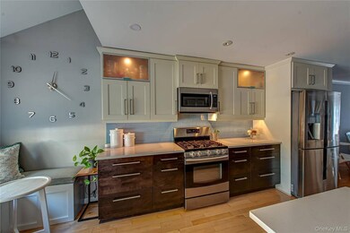 Kitchen with glass insert cabinets, stainless steel appliances, decorative backsplash, light wood finished floors, and recessed lighting