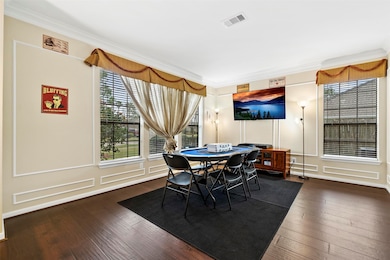 The formal living offers ample room for a study option. This space also features the espresso-stained hardwood flooring, wainscot trim, crown moulding, and ample natural light.