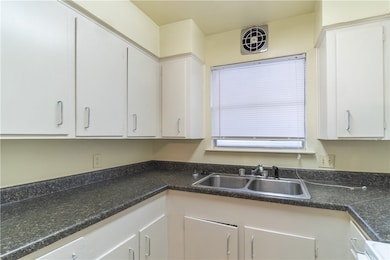 Kitchen with a sink, white cabinets, and dark coun