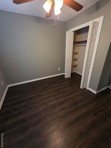 Unfurnished bedroom with dark wood-type flooring, ceiling fan, and a closet