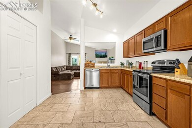 Kitchen with appliances with stainless steel finishes, lofted ceiling, brown cabinetry, a ceiling fan, and a sink