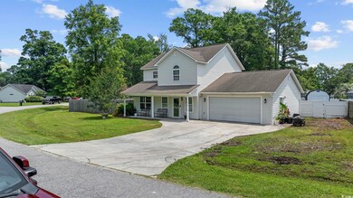 Traditional-style house featuring covered porch, a garage, driveway, a gate, and roof with shingles