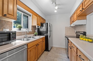 Kitchen features stainless steel appliances, tiled floors, solid wood cabinets.