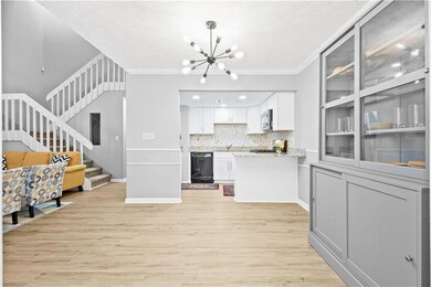Kitchen with dishwasher, stainless steel microwave, a chandelier, light wood-style floors, and white cabinets