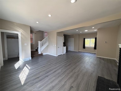 Unfurnished living room featuring recessed lighting, dark wood-style flooring, stairs, and a fireplace