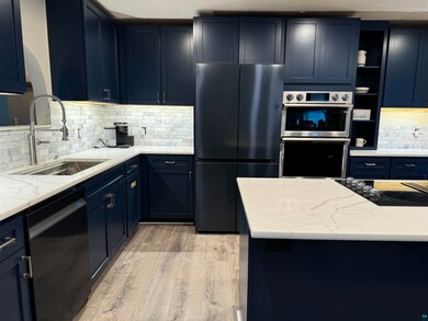 Kitchen with black appliances, sink, backsplash, a