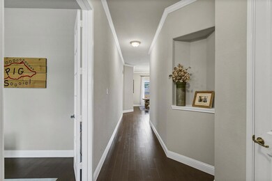 Corridor with dark wood-type flooring and crown mo