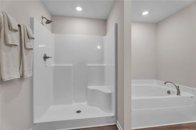 Bathroom featuring a bath, walk in shower, and woo