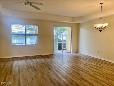 Spare room featuring healthy amount of natural light, wood finished floors, ceiling fan, and a chandelier