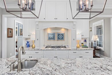 Kitchen with white cabinetry, sink, hanging light 