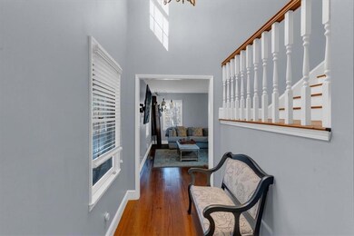 Foyer with dark wood-style floors, a towering ceiling, a chandelier, baseboards, and stairs