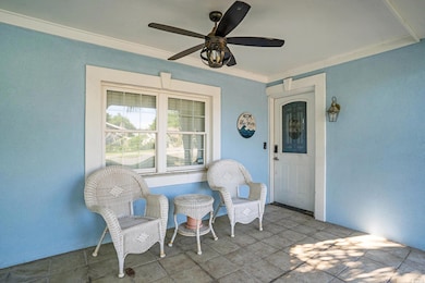 Entrance to property featuring covered porch, stucco siding, and a ceiling fan