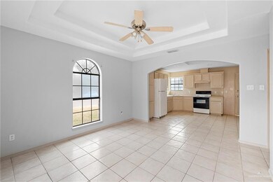 Unfurnished living room featuring a raised ceiling, sink, light tile patterned floors, and ceiling fan