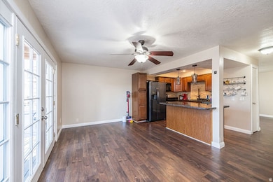 Kitchen with pendant lighting, brown cabinets, refrigerator with ice dispenser, dark stone countertops, and backsplash