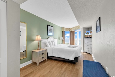 Bedroom with a textured ceiling, a textured wall, wood finished floors, and baseboards