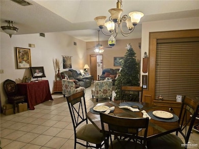 Dining space featuring light tile patterned floors, a textured ceiling, ceiling fan, and a chandelier