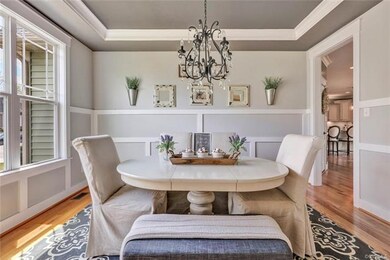 Dining Room with hardwood floors, craftsman trim details, tray ceiling with trim and painted ceiling, crystal chandelier.