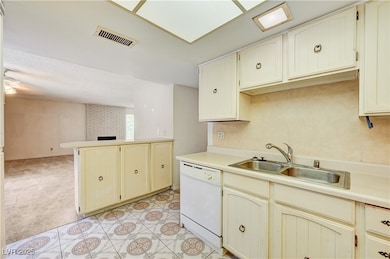 Kitchen featuring dishwasher, light countertops, light carpet, and open floor plan