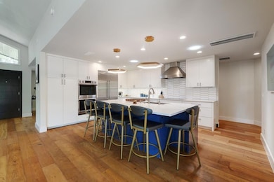 Kitchen with wall chimney exhaust hood, light woo