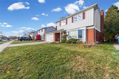 View of front of house with board and batten siding, brick siding, concrete driveway, a front yard, and a garage