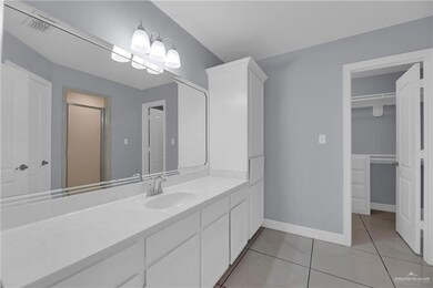 Bathroom featuring baseboards, visible vents, a walk in closet, and vanity